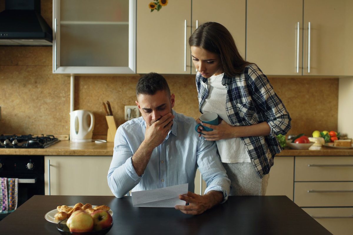 Couple inquiet relisant un courrier dans sa cuisine
